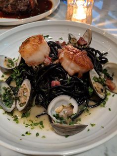 a white plate topped with pasta and clams