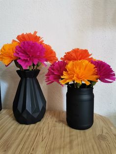 three black vases with different colored flowers in them