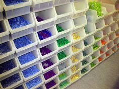 plastic bins filled with lots of different colored beads and other items on the wall