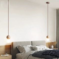 a bed sitting under two hanging lights next to a window