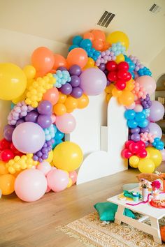 a room filled with lots of balloons on the wall and tables in front of it