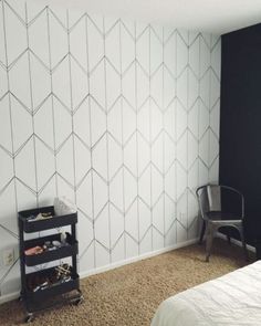 a bedroom with a bed, chair and white wallpaper on the walls is shown