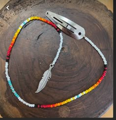 a multicolored beaded necklace on a wooden table with a metal object in the background