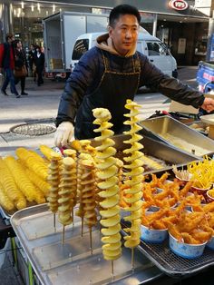 a man standing in front of a table filled with different types of food on skewers