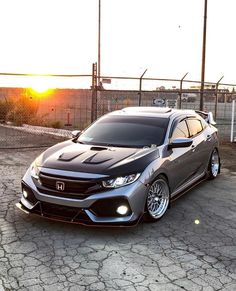 a gray car parked on top of a parking lot next to a chain link fence