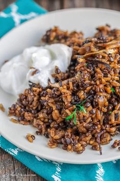 a white plate topped with rice covered in raisins and sour cream on top of a blue napkin