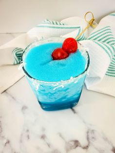 a blue drink with two cherries in it