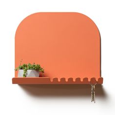 an orange shelf with a potted plant on it and a key hanging from the top