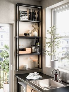 a kitchen sink sitting under a window next to a metal shelf