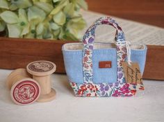 a small purse sitting on top of a table next to a rubber stamp and a wooden spool