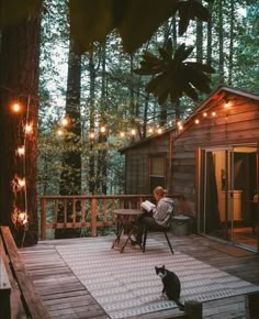 a man sitting in a chair on top of a wooden deck next to a black cat