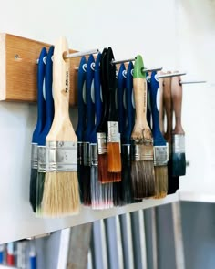 the paint brushes are lined up on the wall to be used as holders for pens and pencils