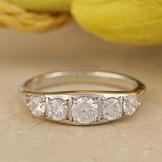 a three stone diamond ring sitting on top of a table next to some lemons