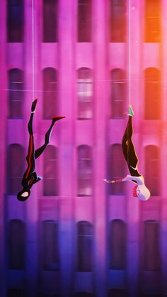 two people are suspended upside down on strings in front of a building with pink and purple lights