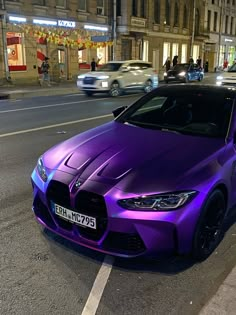 a purple sports car parked on the side of the road in front of some buildings