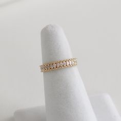 a gold ring with three rows of diamonds in it on a white cloth napkin holder