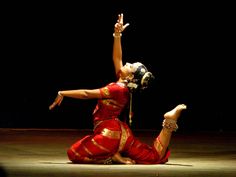 two women in red and gold outfits performing a dance routine on the floor with their hands up