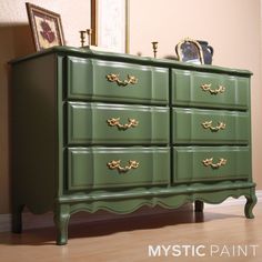 a green dresser with gold handles and knobs on it's drawers in a living room