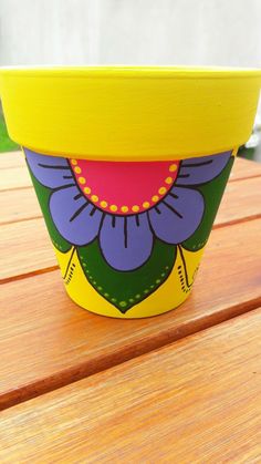 a yellow flower pot sitting on top of a wooden table