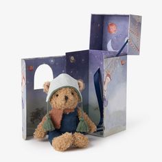 a teddy bear sitting in front of a gift box with an outer space scene on it