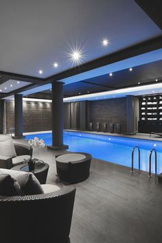 an indoor swimming pool surrounded by furniture and lighting