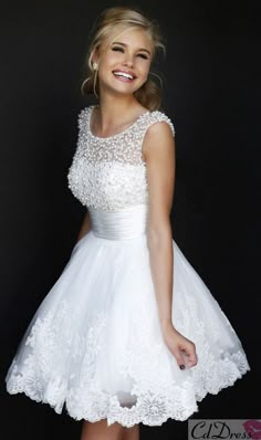 a woman in a short white dress posing for the camera with her hand on her hip