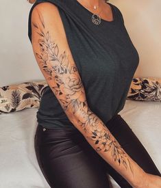 a woman sitting on top of a bed with tattoos on her arm