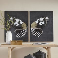 two paintings on a table with vases and books in front of them, one is black and the other is white