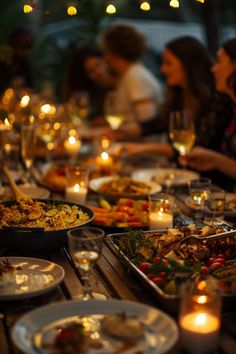 a table full of food and candles with people sitting at the tables in the background