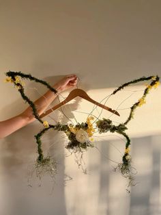 a person's hand holding a piece of art made out of branches and flowers