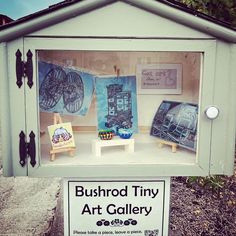 an art gallery display with artwork displayed in it's glass case on the sidewalk