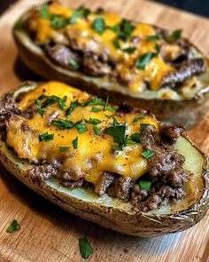 two stuffed potatoes on a cutting board with cheese and ground beef in the middle, topped with fresh parsley