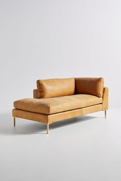 a tan leather couch sitting on top of a white floor next to a wooden frame