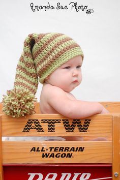 a baby wearing a green and brown knitted hat