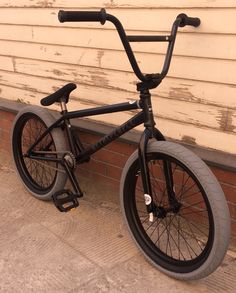 a black bicycle parked next to a brick wall with no wheels on it's rims