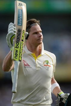 a man holding a cricket bat and wearing headphones on his ears as he walks off the field