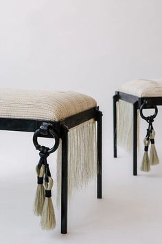 two small stools with tassels on them, one is black and the other is white