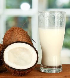 a glass of coconut milk next to a half - eaten coconut on a table with the words top 10 side effects of coconut milk