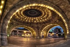 the inside of an old train station with lights on it's ceiling and arches