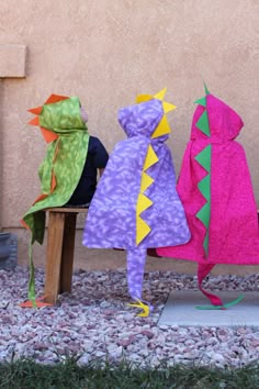 three children's hoodeds sitting on a bench in front of a stucco wall