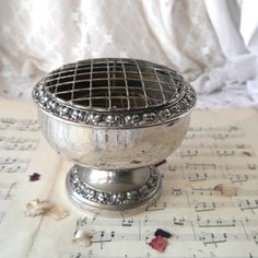 an ornate silver bowl sitting on top of sheet music paper with musical notes in the background