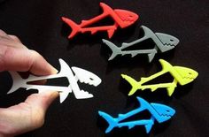 a person holding several different colored fish shaped magnets