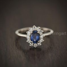 a blue and white diamond ring sitting on top of a wooden table