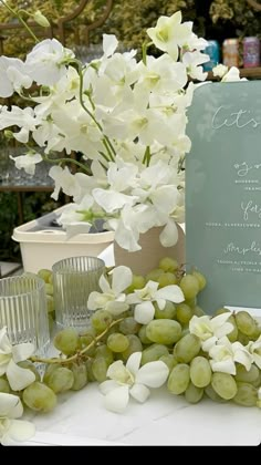 white flowers and green grapes on a table with a blue sign that says, wedding