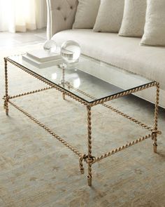 a glass coffee table sitting on top of a carpeted floor next to a couch