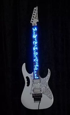 a white electric guitar with a blue light on it's neck and the words rock n roll written in neon letters