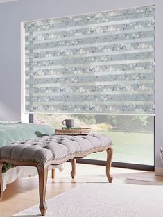 a bedroom with a large window covered in blinds