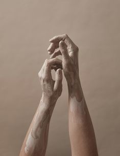 two hands with white paint on them reaching up to touch each other's fingers