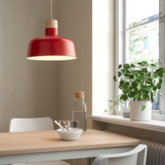 a dining room table with two chairs and a vase on it, next to a window