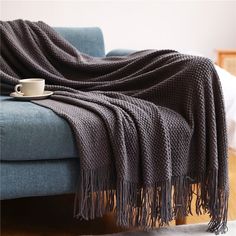 a blanket is draped over a couch with a coffee cup on the end table next to it